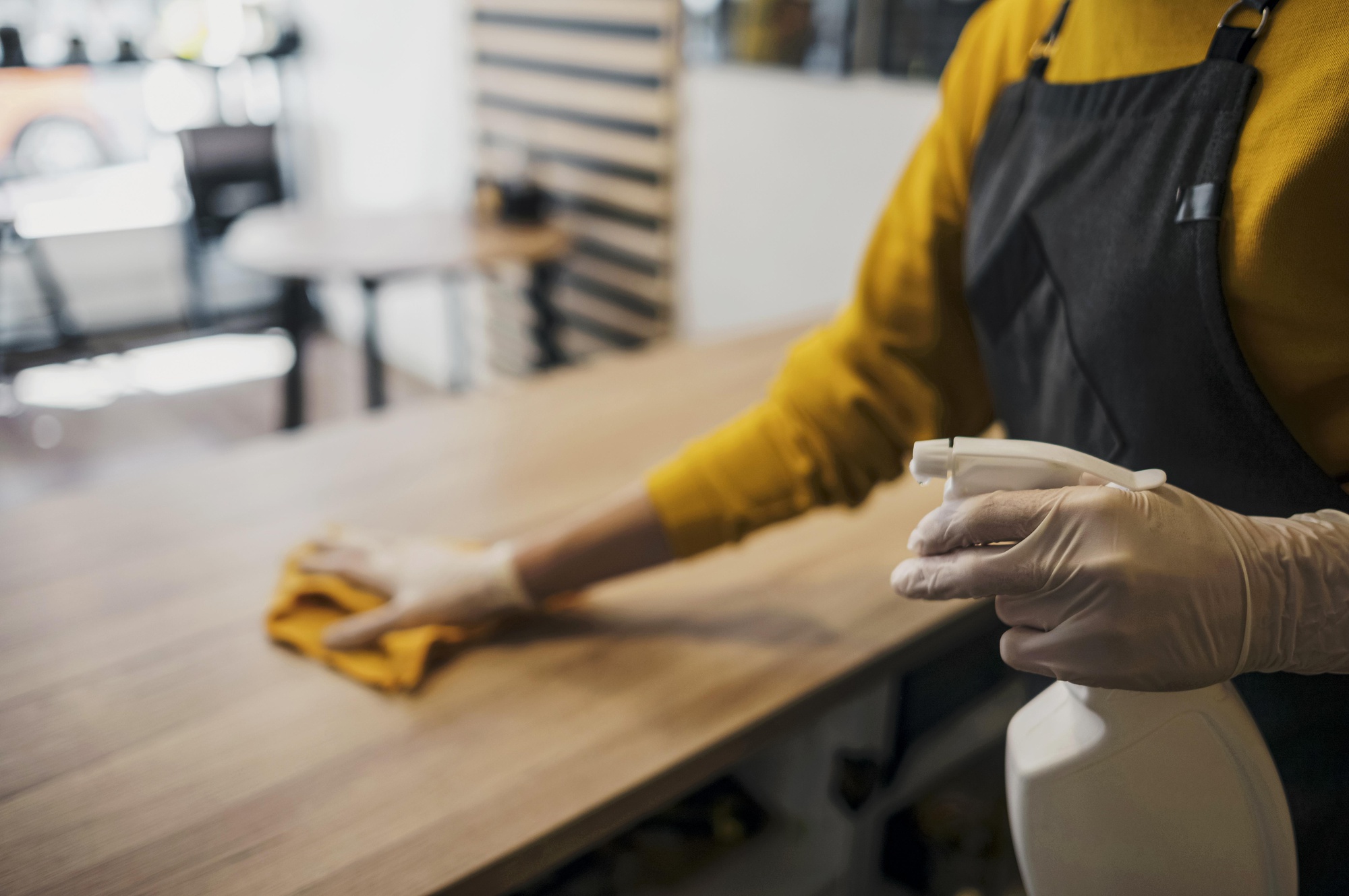 side-view-female-barista-cleaning-table-while-wearing-latex-gloves